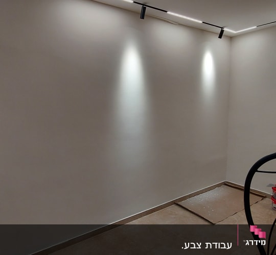 קיר צבוע בלבן עם דלי צבע ומטאטא
